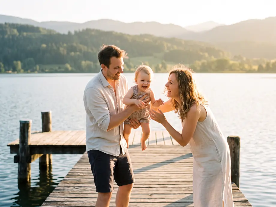 Junge Familie lacht auf einem Holzsteg am See